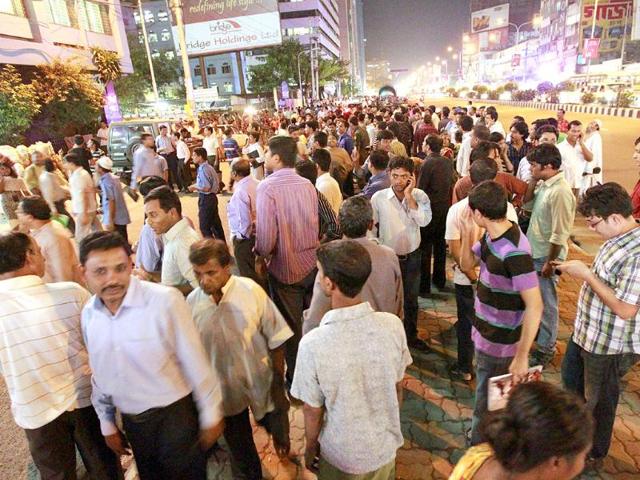 People who rushed out of office buildings following tremors talk on their phones Karwanbazar in Dhaka, Bangladesh. A strong earthquake with a preliminary magnitude of 6.8 hit northeastern India on Sunday near the border with Nepal.