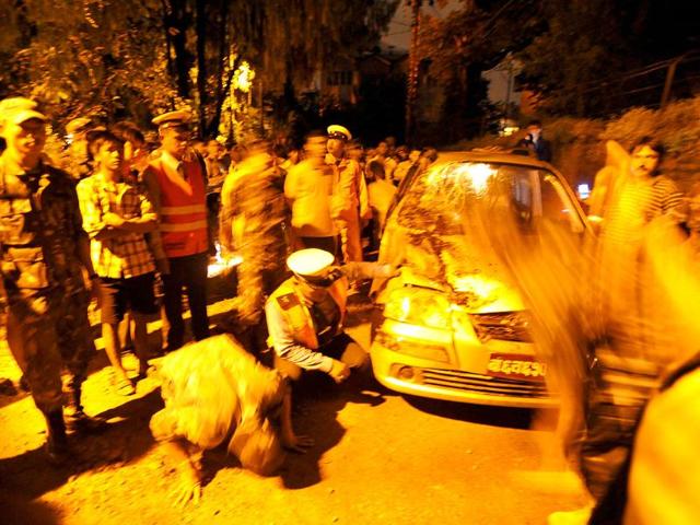 Nepalese police inspect a car damaged by the collapsed wall of the British Embassy after an earthquake in Kathmandu.