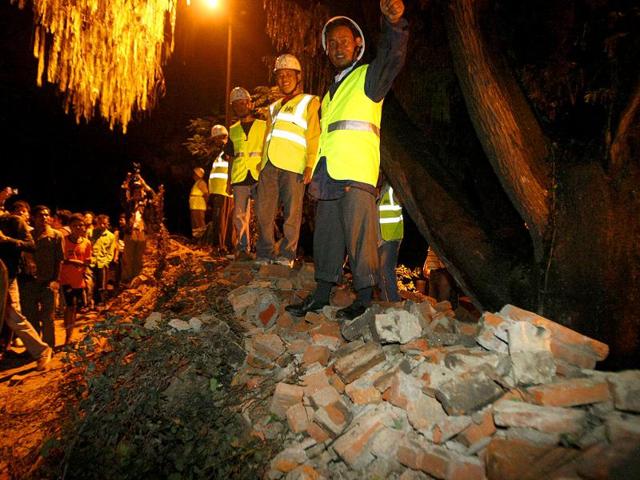 Nepalese rescue workers and people look on after after the British Embassy's compound wall collapsed reportedly killing three pedestrians following an earthquake in Katmandu, Nepal.