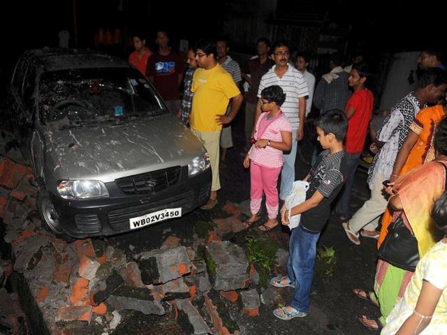 Residents gather near a damaged car and wall rubble in Siliguri after an earthquake hit Sikkim.