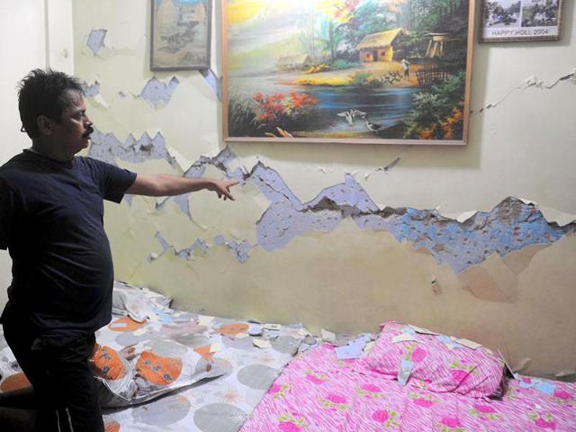 An Indian man points to a crack in the wall of his home after an earthquake hit Sikkim.