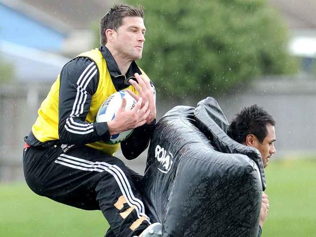 New Zealand All Black player Cory Jane (L) catches the ball as teammate Isaia Toeava (R) carries the padding during a training session in Christchurch.