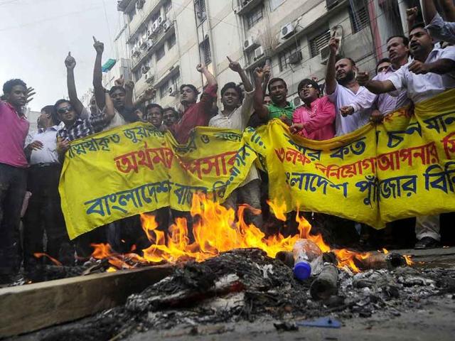 Bangladeshi investors light a fire and shout slogans in the commercial heart of the Bangladeshi capital Dhaka.