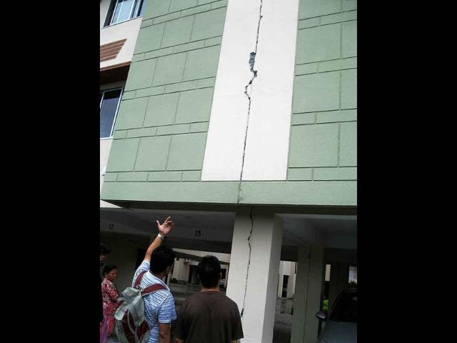 People look at the cracks in a building after last night's earthquake in Siliguri.