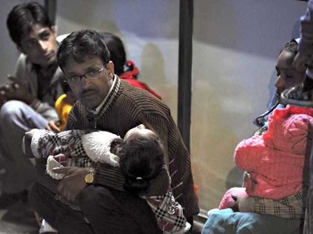 Residents hold their children as they sit outdoors for safety following an earthquake in Gangkok.