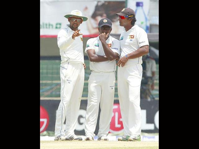 Sri Lanka's Rangana Herath (C), captain Tillakaratne Dilshan (L) and former captain Kumar Sangakkara discuss field settings during the final day of their third and final test cricket match against Australia in Colombo