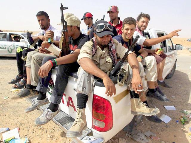 Anti-Gaddafi fighters sit in a truck at a strategic checkpoint after retreating from the north of the besieged city of Bani Walid.