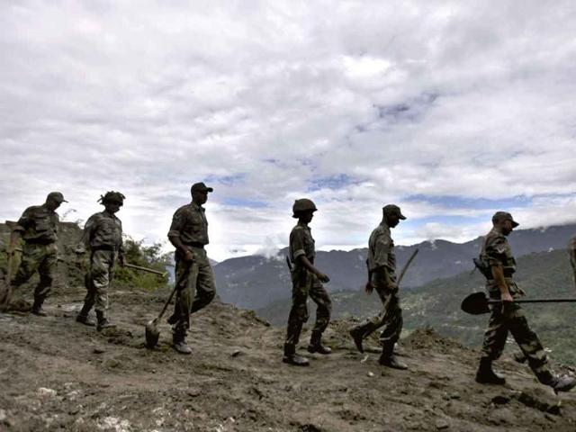 Indian Army personnel walk as they carry spades and other equipments to clear a landslide caused by Sunday’s earthquake in Phengla town, Gangtok.
