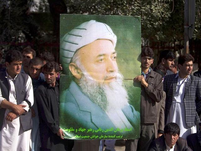 Supporters of Burhanuddin Rabbani, former Afghan president and head of the government's peace council, hold a picture of him as they stand outside his house a day after he was killed in Kabul.