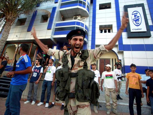 An anti-Gaddafi fighter shouts and gestures in front of a house believed to belong to a Gaddafi loyalist in Tripoli.