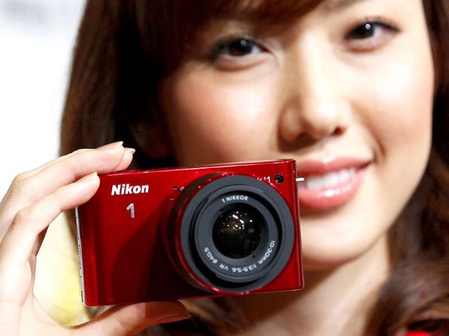 A model poses with Nikon Corp's new Nikon 1 J1 camera, its first lightweight mirrorless interchangeable lens version, at its unveiling ceremony in Tokyo.