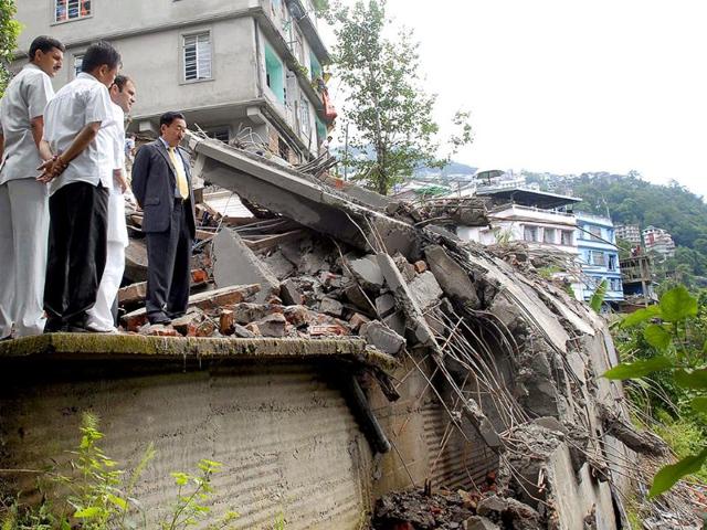 Congress general party Rahul Gandhi (3L) and chief minister of Sikkim Pawan Chamling (R) stand with officials as they inspect damaged homes in Lumsey on the outskirts of Gangtok.