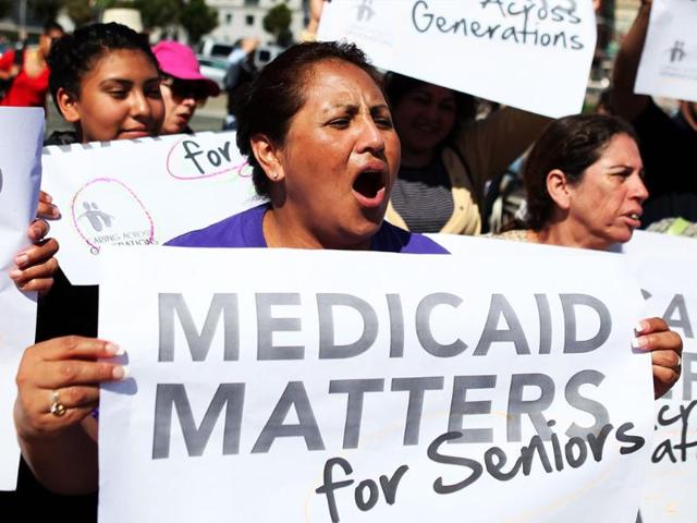 Protestors carry signs as they demonstrate against proposed cuts to Medical and Medicare outside San Francisco city hall in California.