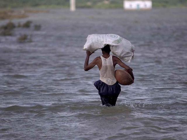 A displaced man wades through flood water, carrying belongings in Tando Muhammad Khan near Hyderabad, Pakistan.