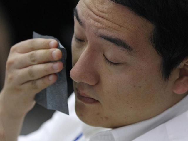 A currency dealer reacts as he looks at screens at a dealing room of a bank in Seoul.