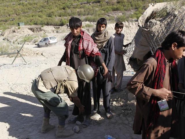 An Afghan security contractor checks teenagers entering US military's Combat Outpost (COP) Pirtle King in Ghaziabad district in Kunar province, eastern Afghanistan. Afghan teenagers go to the camp daily to do odd jobs.