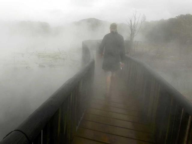 A tourist walks through steam on a bridge above thermal water in a park in Rotorua. The geothermal activity and bubbling mud volcanoes are the main attractions of the central area of the northern island of New Zealand.