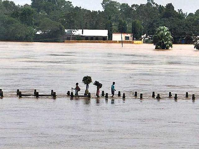 Villagers wade through overflowing flood water on a fly over of Baitarani river at Katarpur village, Jajpur district in Orissa.