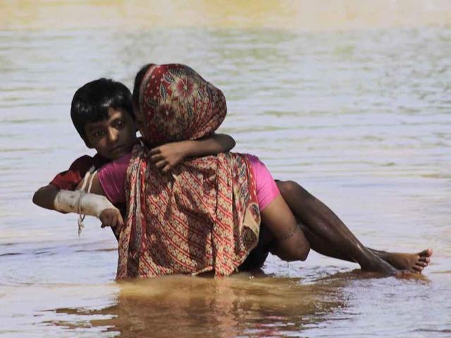 A woman carries her injured son through flood waters at Pahanga village in Orissa's Jajpur district. Massive floods have left millions homeless in one of the worst cases of flooding in the past 3 decades in Orissa.