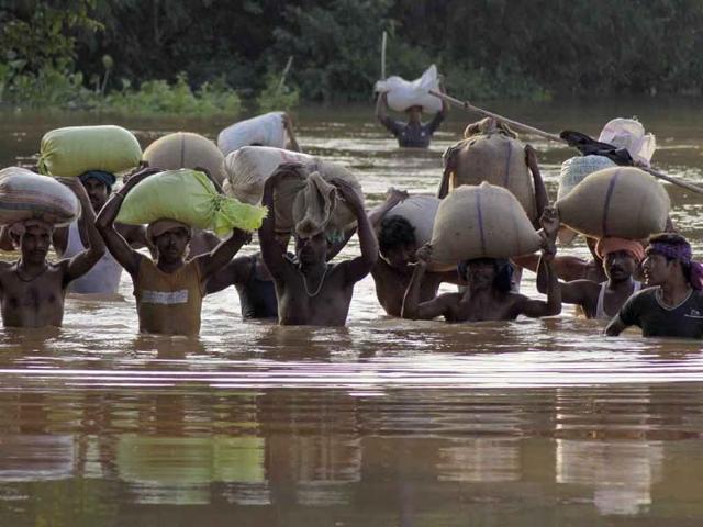 Villagers carry relief materials through flood waters at Rasulpur village in Orissa's Jajpur district. Monsoon rains have left hundreds of thousands of people marooned by the raging waters.