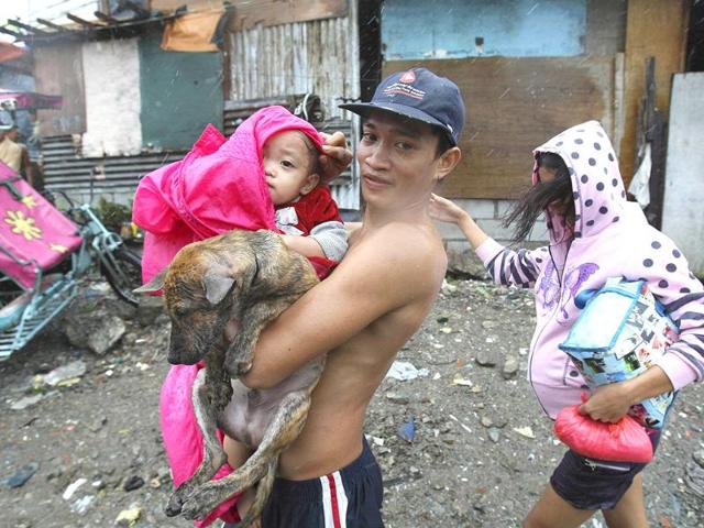 A family evacuates to safety with their pet dog at the height of typhoon Nesat Tuesday in Manila, Philippines.
