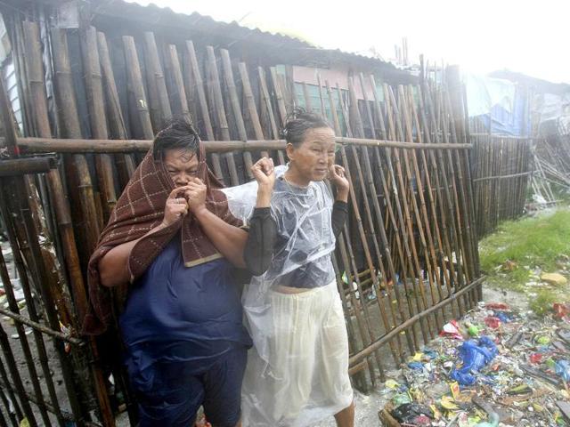 Women brave the strong winds and rain as they prepare to evacuate to safer grounds at the height of typhoon Nesat in Manila, Philippines.