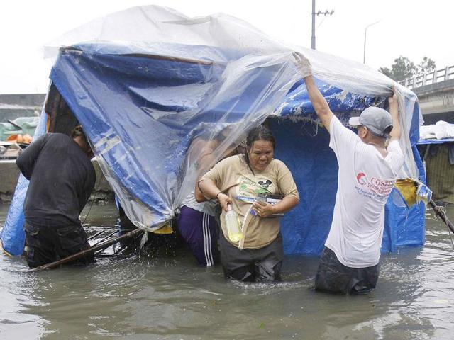 Residents living in makeshift houses beside a river carry belongings as they evacuate to higher grounds in Navotas, north of Manila, Philippines as Typhoon Nesat hits the country.