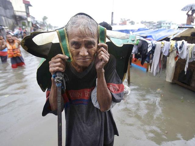 An old Filipino man living beside a river evacuates his flooded home in Navotas, north of Manila, Philippines as Typhoon Nesat hits the country.