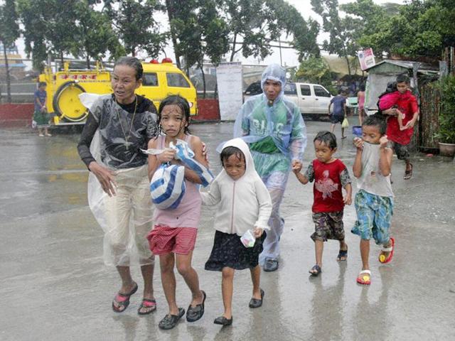A family living near the sea front carry their belongings as they evacuate from floodwaters brought by Typhoon Nesat, locally known as Pedring, in Tondo city, metro Manila.