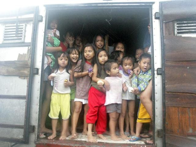 Children look out from the back of a delivery truck as they evacuate their shanties after floodwaters brought by Typhoon Nesat, locally known as Pedring, hit Baseco, Tondo city, in metro Manila.