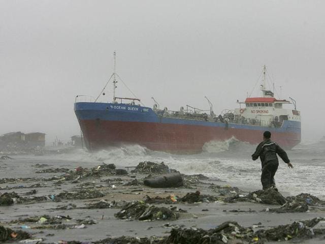 A resident approaches an oil tanker after it broke off its anchor and slammed a row of shanties as typhoon Nesat hit Philippines.