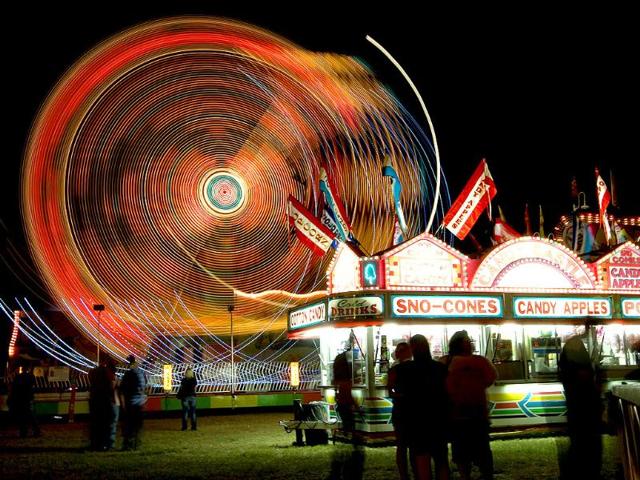 Patrons to the Red River Valley Fair in Paris, Texas stand in line for food and attractions while the Ali Baba ride spins riders around.