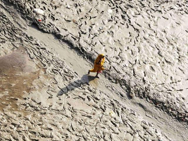 A woman walks on the muddy banks of the Ganges river before taking a holy dip during the Navratri festival, in Allahabad.