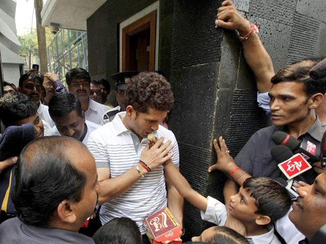 Sachin Tendulkar, center, receives sweets from school children who arrived to greet him after he moved to his new house in Bandra area in Mumbai.