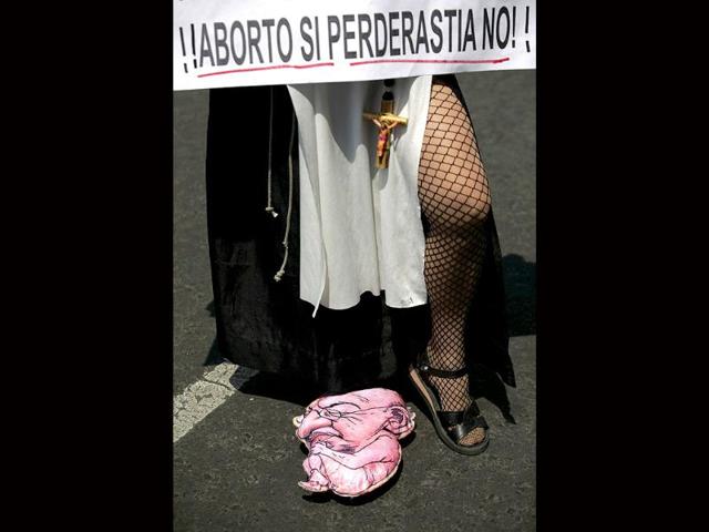 A pro-choice activist, clad in a nun-outfit, holds a sign reading "Abortion yes; Pederasty no," while a baby figure depicting Mexico's President Felipe Calderon lies on the floor during a protest in Mexico City. Mexico's SC upheld a law that says that life begins at conception, signaling a victory for anti-abortion campaigners. Seven out of eleven ministers deemed the measure unconstitutional but eight votes were needed to overturn it.