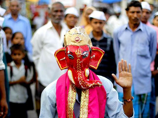 A devotee wears a mask of elephant-headed Hindu God Ganesha as he celebrates along with others the first day of Navratri festival in Mumbai.