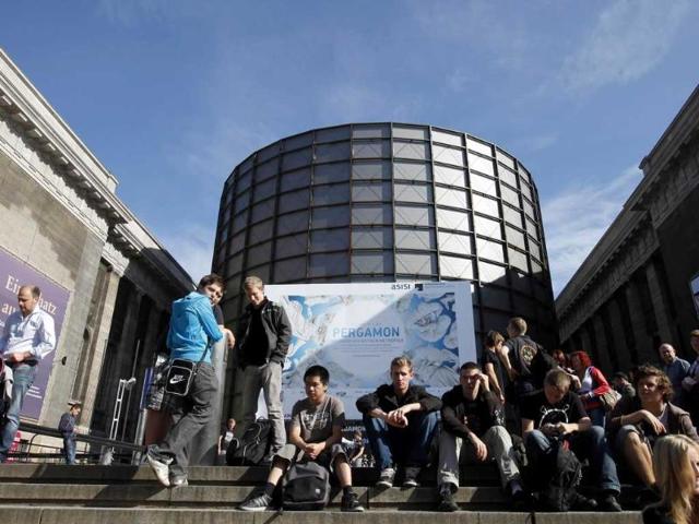 Visitors sit outside building with the 'Pergamon - Panorama of the Ancient Metropolis' 360 degrees panorama created by artist Yadegar Asisi from outside at an exhibition by the Collection of Classical Antiquities - National Museum during the press preview in Berlin. The condensed scenes depicted in Asisi panorama are 30 metres in height and 100 metres in length showing natural landscapes and the acropolis in Pergamon in the year 129 AD.
