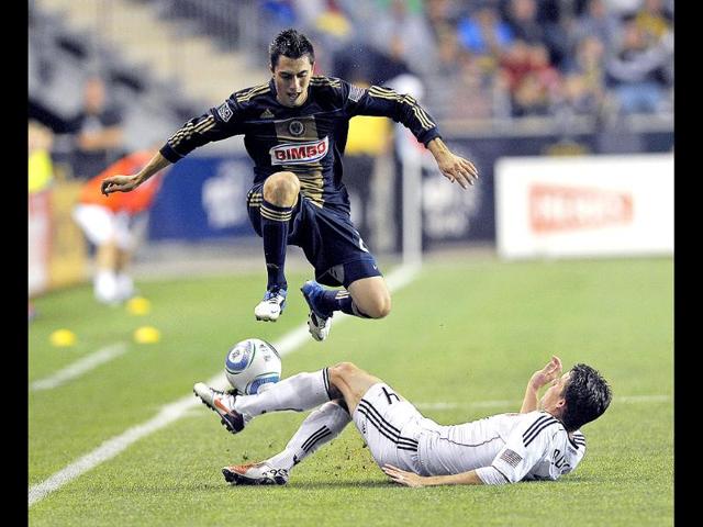 Philadelphia Union's Michael Farfan, left, jumps over DC United's Marc Burch (4) during the second half of an MLS soccer match in Chester. The Union won, 3-2.