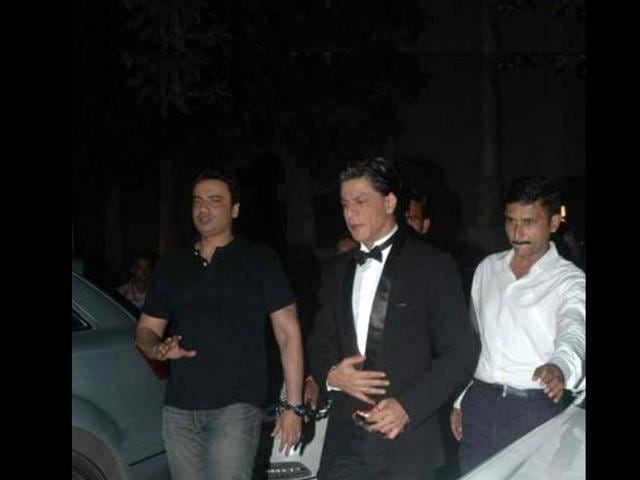 SRK looks good in a black suit over a crisp white shirt with a black bow.