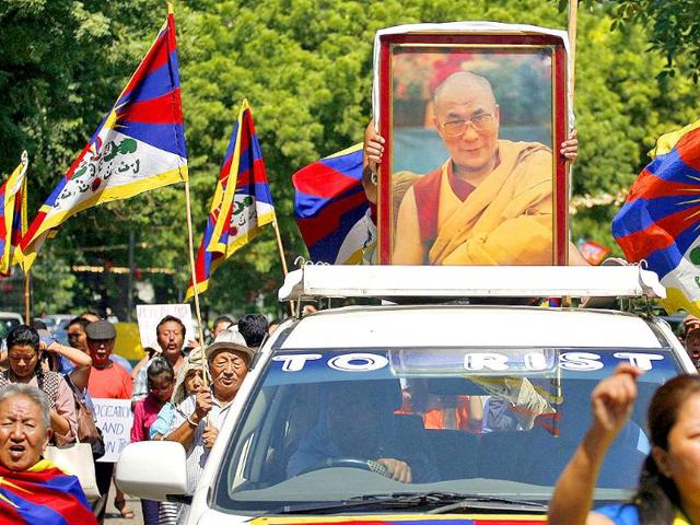 A Tibetan exile holds a portrait of Tibet's exiled spiritual leader the Dalai Lama atop a car during a protest in New Delhi.