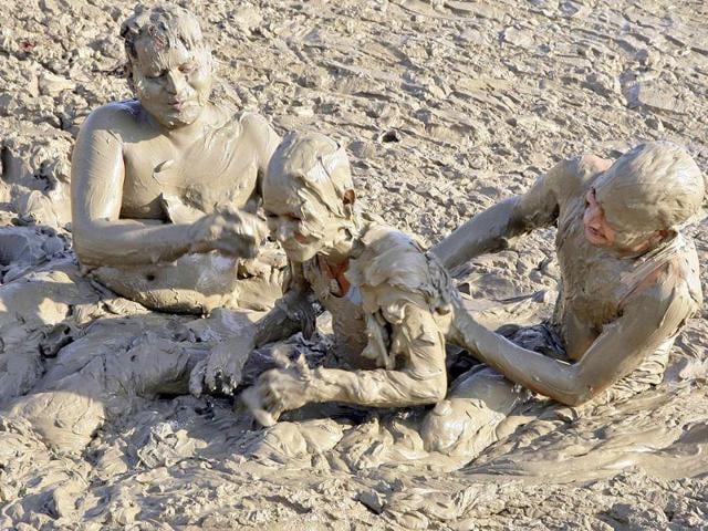 Men play in the mud on the banks of the Ganges river, before taking a dip in the river, in Allahabad.