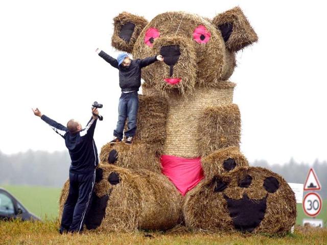 A man prepares to take pictures of his son in front of a straw figure, in Molodechno. Straw figures are installed to mark the agricultural holiday of the end of the harvest on state collective farms.