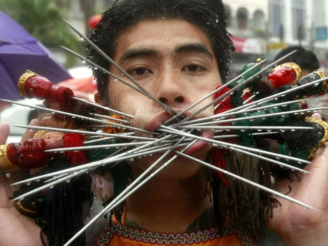 A devotee of the Jui Tui Chinese Shrine has his cheeks pierced with skewers at a procession during the Phuket Vegetarian Festival, southern Thailand.