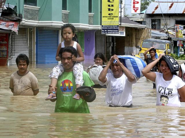 Residents wade through floodwaters with their items as flooding continues for the fourth day at Calumpit township, Bulacan province north of Manila, Philippines.