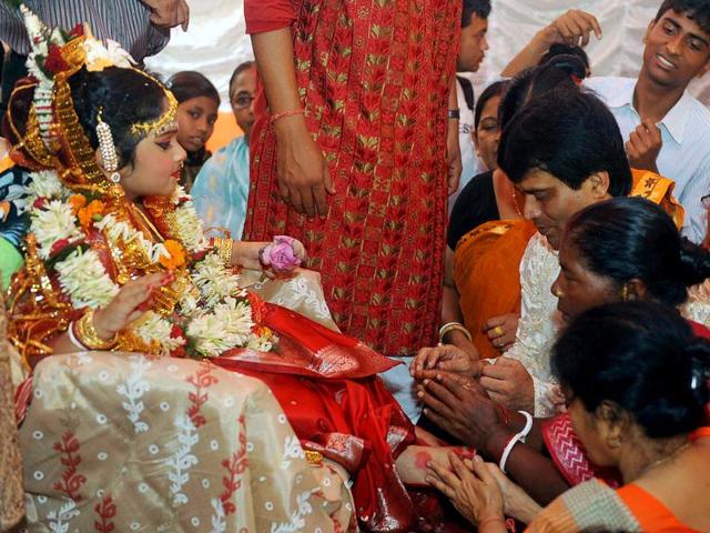 Devotees touch the feet of a young girl, known as a 'kumari', dressed as the Hindu goddess Durga during a ritual for the Durga Puja festival in Siliguri.