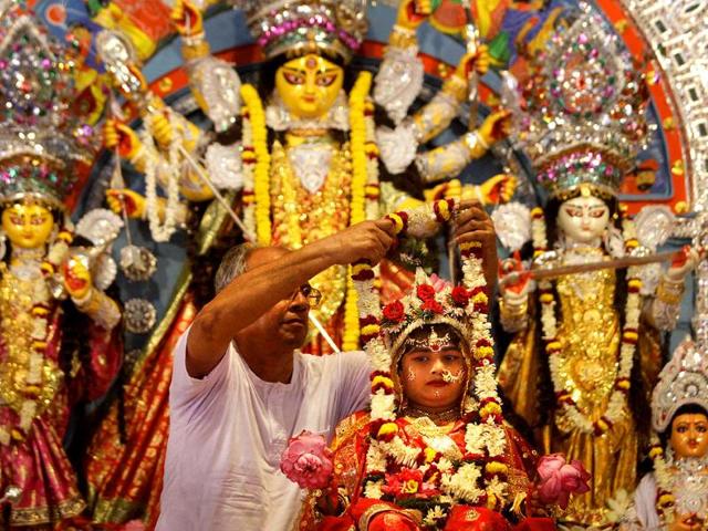 A priest puts a garland on a Kumari, a virgin girl worshipped as an incarnation of Goddess Durga, during Durga Puja festival in Belur.