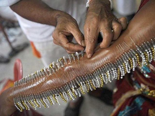 A man pierces the arm of a devotee of the Chinese Jui Tui Shrine with needles ahead of a street procession marking the annual Vegetarian Festival in the southern Thai town of Phuket.