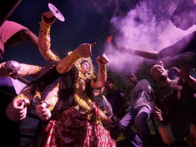 A devotee holding incense sticks dances before an idol of Hindu goddess Durga being brought for immersion in River Brahmaputra in Gauhati.