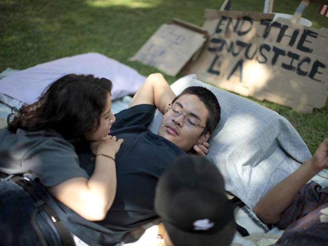 Iman Issa (L), 19 and Victor Valdez, 20, rest at the Occupy LA protest camp in Los Angeles, California. The Occupy Wall Street movement that began in New York last month with a few people has expanded to protests across the country with marches and camps taking shape from Tampa, Florida to Portland, Oregon, and Los Angeles to Philadelphia.