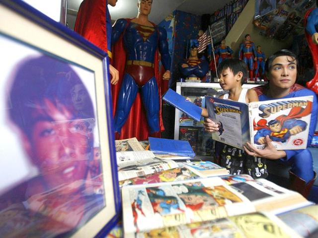 Herbert Chavez holds a Superman book as he shows his collection to a boy inside his house in Calamba Laguna, south of Manila.